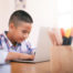 Boy using his laptop to learn online.