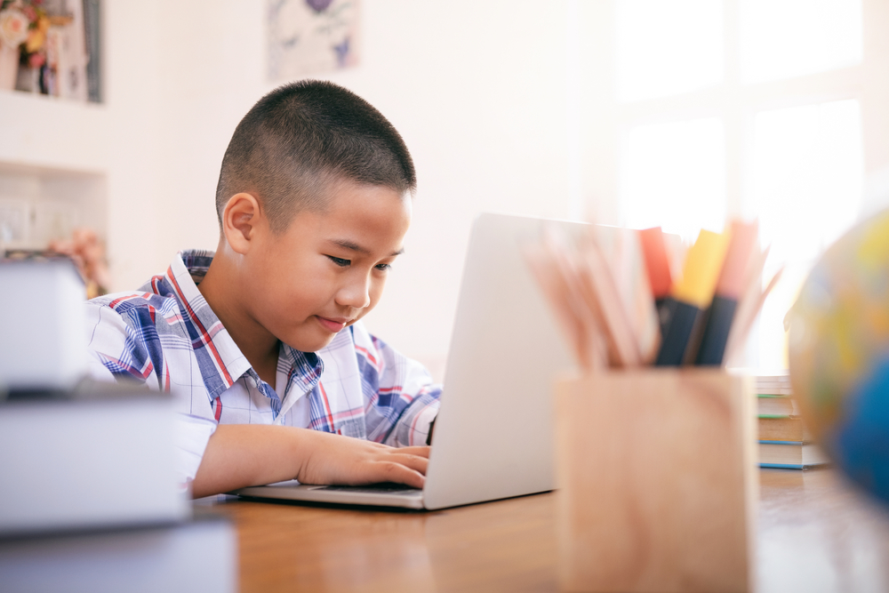 Boy using his laptop to learn in online after school programs