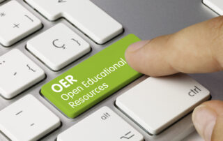 OER Open Educational Resources Written on Green Key of Metallic Keyboard. Finger pressing key.
