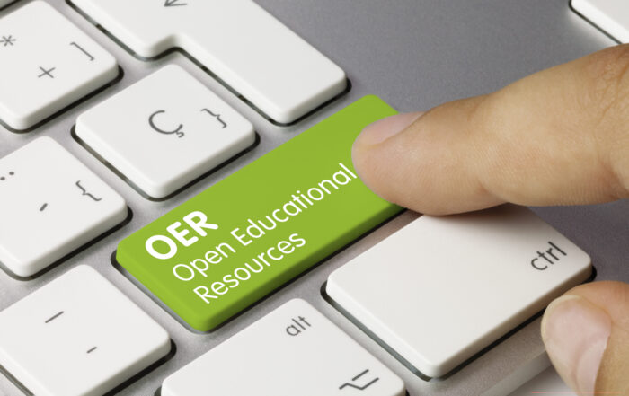 OER Open Educational Resources Written on Green Key of Metallic Keyboard. Finger pressing key.