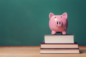 Pink Piggy bank on top of books with chalkboard in the background.