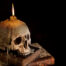 scary stories, creepy skull on a stack of books with candle burning on it