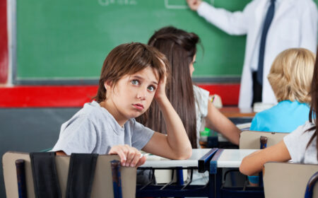 why do some students hate their teachers? picture of young student in class, bored and annoyed by their teacher.