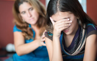 A mother comforts her crying teenage daughter
