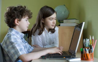 two students playing math games on a computer
