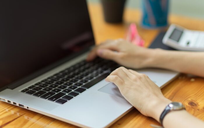 Close up of person taking test on computer, typing on laptop keyboard