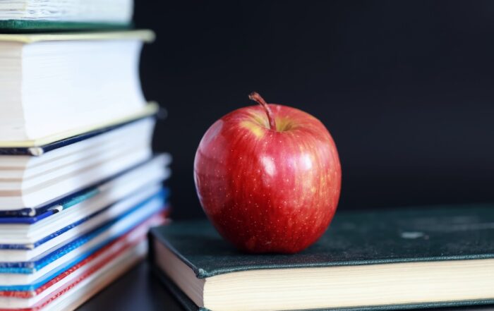 A stack of back to school books and an apple