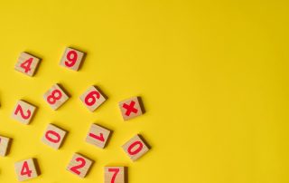 Making math fun! Wooden numbers on yellow background.