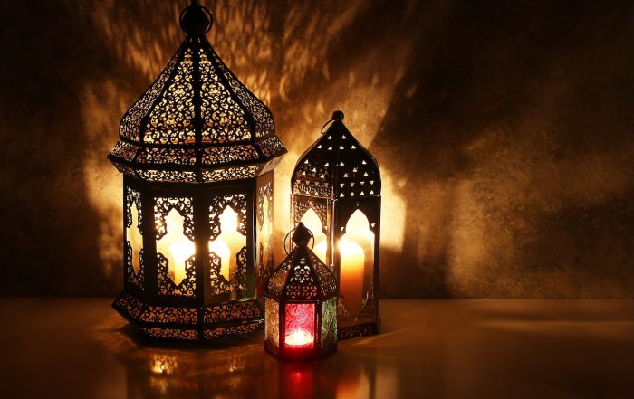 Ornamental Arabic lanterns with burning candles on table glowing at night, festive greeting card, invitation for Muslim holy month Ramadan Kareem. Iftar dinner background with golden glow.