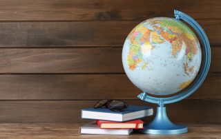 Globe, books and eyeglasses on wooden table. Books about travel.