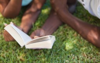 Two Black readers in the grass on a sunny June day. Books to read for Juneteenth cover image.